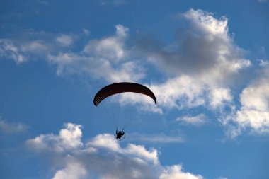 Mavi gökyüzünde paraglider silueti.