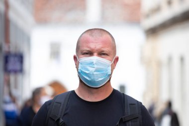 COVID-19 Pandemik Coronavirüs. Şehirde SARS-CoV-2 virüsünün yayılması için maske takan bir adam var. Koronavirüs hastalığına karşı yüzünde koruyucu maske olan bir adam..