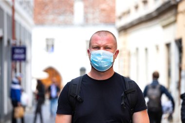 COVID-19 Pandemik Coronavirüs. Şehirde SARS-CoV-2 virüsünün yayılması için maske takan bir adam var. Koronavirüs hastalığına karşı yüzünde koruyucu maske olan bir adam..