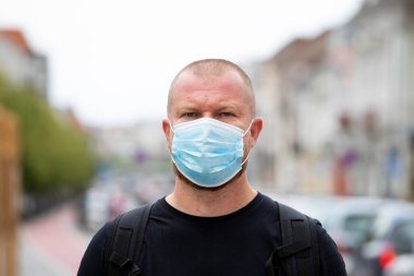 COVID-19 Pandemik Coronavirüs. Şehirde SARS-CoV-2 virüsünün yayılması için maske takan bir adam var. Koronavirüs hastalığına karşı yüzünde koruyucu maske olan bir adam..
