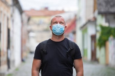 COVID-19 Pandemik Coronavirüs. Şehirde SARS-CoV-2 virüsünün yayılması için maske takan bir adam var. Koronavirüs hastalığına karşı yüzünde koruyucu maske olan bir adam..