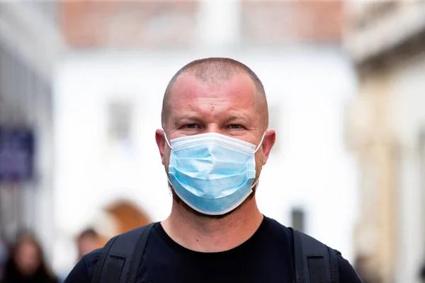 COVID-19 Pandemic Coronavirus. Man in city street wearing face mask protective for spreading of disease virus SARS-CoV-2. Man with protective mask on face against coronavirus disease.