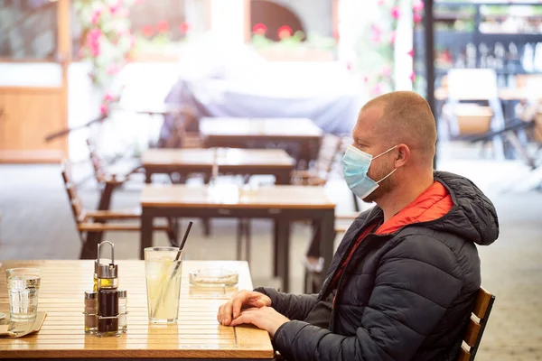 Man sitting separated in restaurant  wearing medical protective face to protect infection from coronavirus covid-19, restaurant and social distancing concept