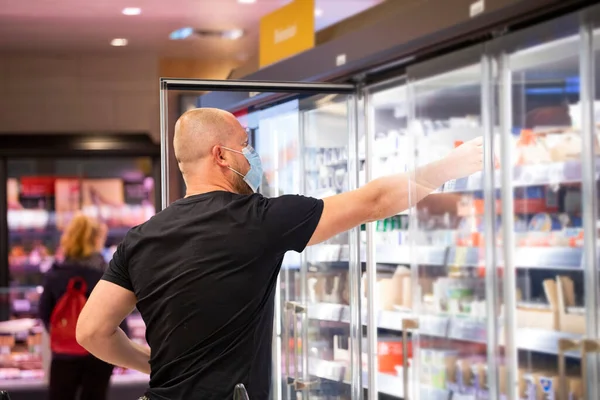 Buyer wearing a protective mask shopping in supermarket during coronavirus pneumonia outbreak. Protection and prevent measures while epidemic time.