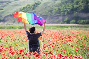 Haşhaş tarlasında elinde Gay Gökkuşağı Bayrağı olan bir kadın. Biseksüel, gey, lezbiyen, transseksüel sembolü. Aynı cinsiyet çiftleri için mutluluk, özgürlük ve aşk kavramı