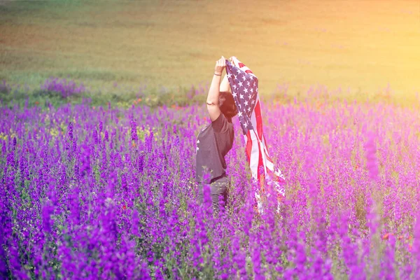 在晴朗 阳光明媚的夏天 迷人的女人在美丽的田野里举着美国国旗 庆祝独立日 国定假日概念 — 图库照片