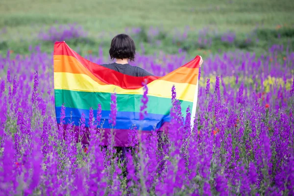 美しい夏のフィールドでゲイレインボーフラッグを保持する女性 バイセクシャル レズビアン トランスセクシャルのシンボル 同じセックスカップルのための幸福 自由と愛の概念 — ストック写真