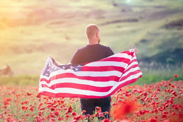 晴れた日には美しいケシ畑でアメリカ国旗を掲揚する魅力的な男性 独立記念日 国民の休日の概念を祝う — ストック写真