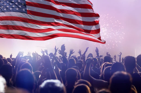 Crowd of people celebrating Independence Day. United States of America USA flag with fireworks background for 4th of July.