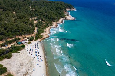 Yazın şeffaf mavi suyla deniz koyunda yüzen insanların olduğu kumlu sahil manzarası. Thassos Adası, Yunanistan 'da Seyahat. 