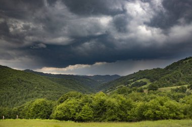 Yeşil yaz tepelerinde fırtınadan önce dramatik bir gökyüzü.