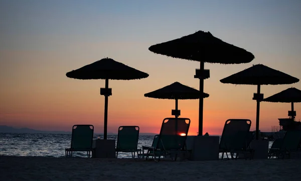 日光浴床的轮廓和日出时的雨伞 假日旅游 海滨放松的概念 — 图库照片