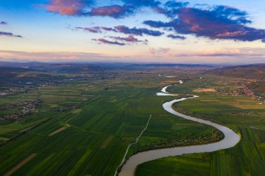Romanya 'nın Transilvani kentinde nehrin kıvrımlı suları üzerine gün batımı, hava ve atmosfer manzarası. Romanya 'nın güzel kırsal-drone manzarası.