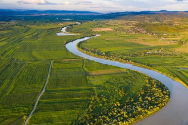Romanya 'nın Transilvani kentinde nehrin kıvrımlı suları üzerine gün batımı, hava ve atmosfer manzarası. Romanya 'nın güzel kırsal-drone manzarası.