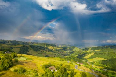 Uçan, uçsuz bucaksız otlakların yeşil tarlaları ve otlakları, arka planda fırtınalı gökyüzü.