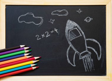 Tahtaya elle çizilmiş roket ve okul malzemeleriyle okul konseptine geri dönelim. Düz yatıyordu.