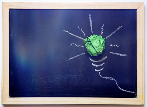 Green paper light bulb on blackboard. Corporate Social Responsibility, responsible business, eco friendly, sustainable living concept.