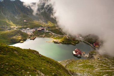 Dramatik sisli havada Balea Gölü. Romanya 'nın Fagaras dağındaki güzel varış yeri. Tepenin tepesinden bulutların arasından bak.