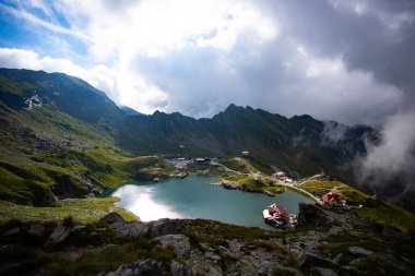 Kaya tepesinde kalan adam buzulların arasındaki güzel gölün tadını çıkarıyor..