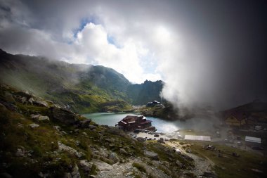 Dramatik sisli havada Balea Gölü. Romanya 'nın Fagaras dağındaki güzel varış yeri. Tepenin tepesinden bulutların arasından bak.