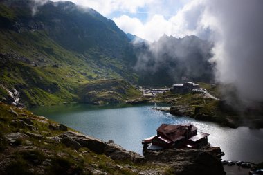 Dramatik sisli havada Balea Gölü. Romanya 'nın Fagaras dağındaki güzel varış yeri. Tepenin tepesinden bulutların arasından bak.