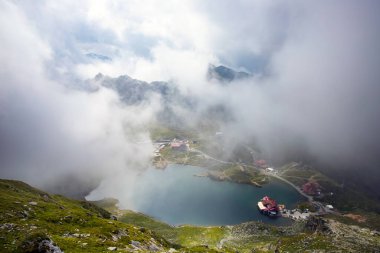 Dramatik sisli havada Balea Gölü. Romanya 'nın Fagaras dağındaki güzel varış yeri. Tepenin tepesinden bulutların arasından bak.