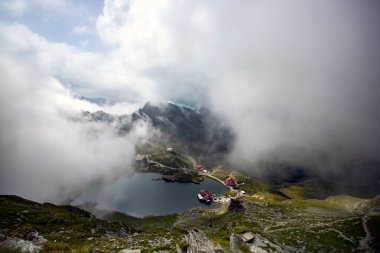 Dramatik sisli havada Balea Gölü. Romanya 'nın Fagaras dağındaki güzel varış yeri. Tepenin tepesinden bulutların arasından bak.