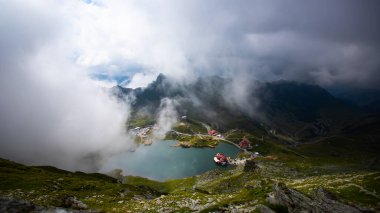 Dramatik sisli havada Balea Gölü. Romanya 'nın Fagaras dağındaki güzel varış yeri. Tepenin tepesinden bulutların arasından bak.
