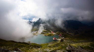 Dramatik sisli havada Balea Gölü. Romanya 'nın Fagaras dağındaki güzel varış yeri. Tepenin tepesinden bulutların arasından bak.