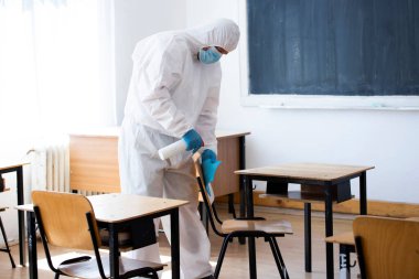 İşçi COVID-19 'un yayılmasına karşı önleyici önlemlerin bir parçası olarak dezenfektan sıkar, okullarda yeni bir koronavirüs. Yeni okul sezonuna hazırlanıyorum..