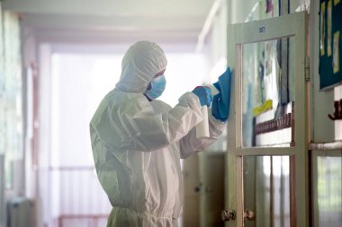 İşçi COVID-19 'un yayılmasına karşı önleyici önlemlerin bir parçası olarak dezenfektan sıkar, okullarda yeni bir koronavirüs. Yeni okul sezonuna hazırlanıyorum..