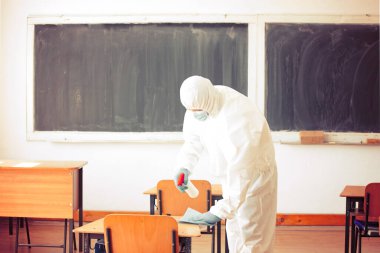 İşçi COVID-19 'un yayılmasına karşı önleyici önlemlerin bir parçası olarak dezenfektan sıkar, okullarda yeni bir koronavirüs. Yeni okul sezonuna hazırlanıyorum..