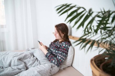 Akıllı telefon kullanan genç kız, gece geç saatte yatakta yatan tablet. Çocukların ekran bağımlılığı konsepti..