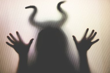 Karanlıkta, pencerenin arkasında boynuzları olan ürkütücü bir figür. Cadılar Bayramı geçmişi 