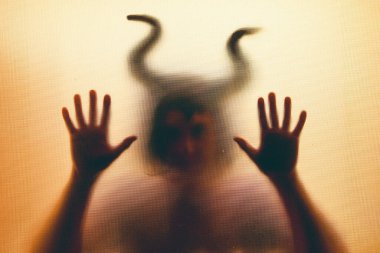 Karanlıkta, pencerenin arkasında boynuzları olan ürkütücü bir figür. Cadılar Bayramı geçmişi