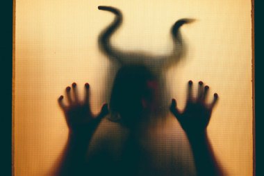 Karanlıkta, pencerenin arkasında boynuzları olan ürkütücü bir figür. Cadılar Bayramı geçmişi