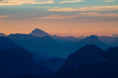 İtalya 'nın Dolomite dağlarında, görkemli dağ zirvelerinin silueti, canlı günbatımının arka planına karşı.