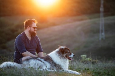 İnsan ve köpeği güzel günbatımının tadını çıkarıyor.