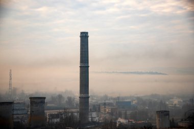Urban landscape with air pollution from power plant chimneys.