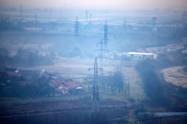 High-voltage power lines in the fog. Electricity distribution station .