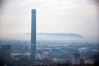 Urban landscape with air pollution from power plant chimneys.