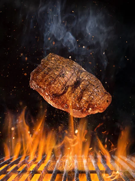 Taste steak de boeuf volant au-dessus de la grille en fonte avec des flammes de feu . — Photo