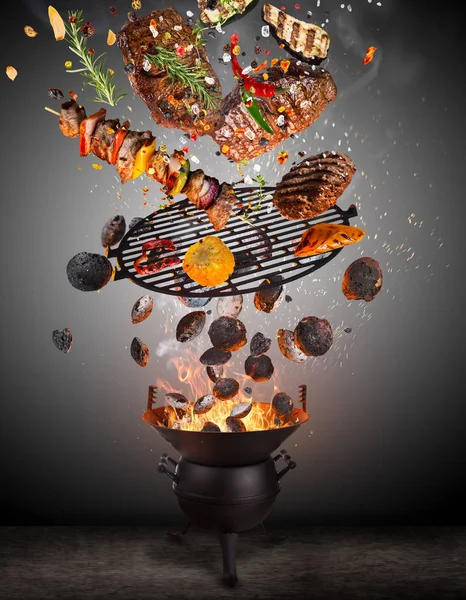 Parrilla para hervidor con briquetas calientes, rejilla de hierro fundido y sabrosos pinchos volando en el aire . — Foto de Stock