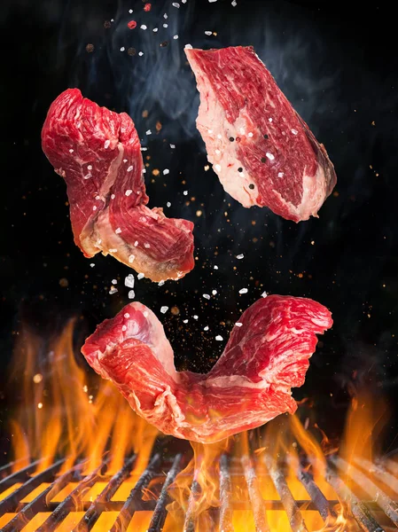 Rohes, schmackhaftes Rindersteak fliegt mit Feuerflammen über gusseisernen Rost. — Stockfoto