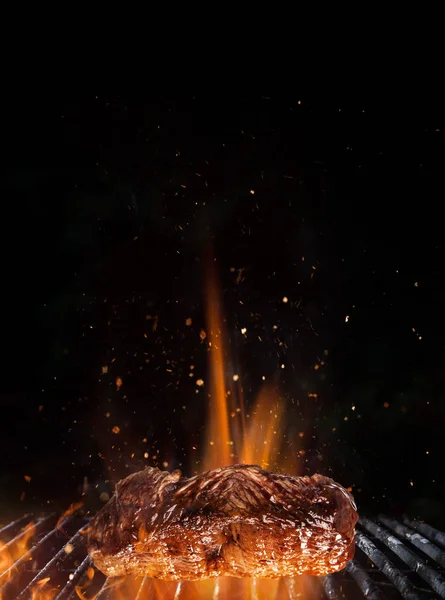 Gustosa bistecca di manzo su griglia in ghisa con fiamme di fuoco. — Foto Stock