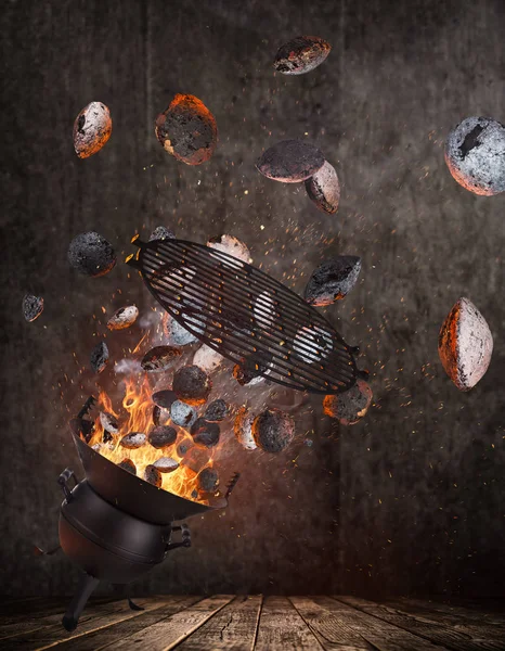Kettle grill with hot briquettes and cost iron grid flying in the air. — Stock Photo, Image