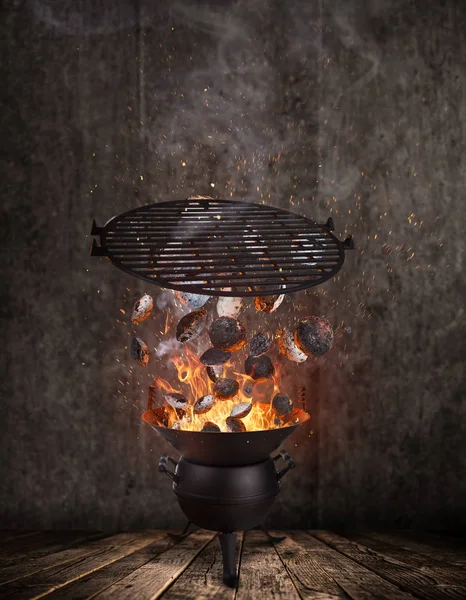 Kettle grill with hot briquettes and cost iron grid flying in the air. — Stock Photo, Image