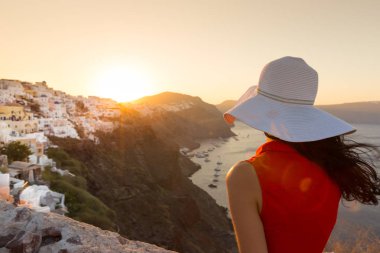 Santorini seyahat ediyor. Kırmızı elbiseli esmer kadın ünlü beyaz Oia köyünü ziyaret ediyor..
