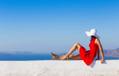 Santorini seyahat ediyor. Kırmızı elbiseli esmer kadın ünlü beyaz Oia köyünü ziyaret ediyor..