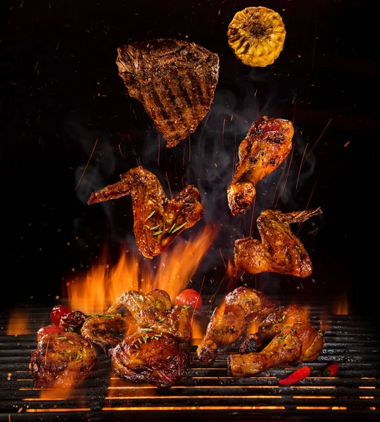 Chicken legs and wings on the grill with flames — Stock Photo, Image